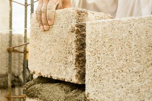 Placing a concrete block on a wall. The block is placed with a mortar of cement and sand when it is fresh.